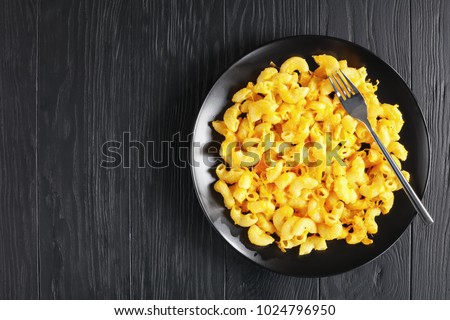 classic Baked Homemade Macaroni and Cheese on black plate with fork on dark wooden table, view from above Royalty-Free Stock Photo #1024796950
