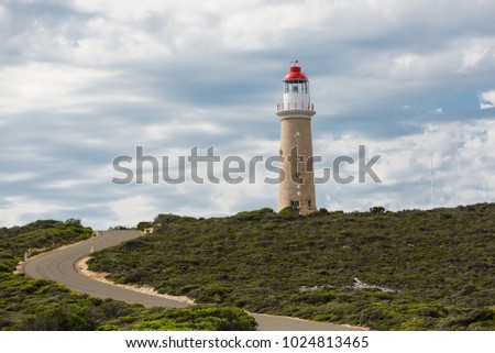 The Cape du Couedic Lighthouse, with road leading up the hill and cloudy sky.