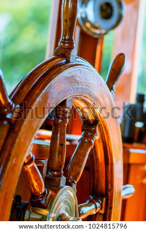 Red, old, lacquered, wooden steering wheel on a marine yacht close-up, barometer and binoculars in the background