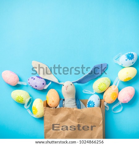 Easter bunny in a paper bag with Easter eggs. Blue background. Space for text. The inscription on the package. 