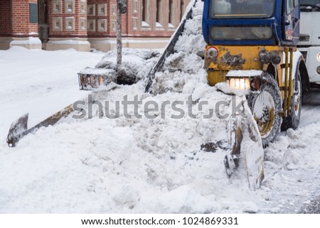 Tractor cleaning the streets of large amounts of snow in city after snowstorm. Winter time concept.