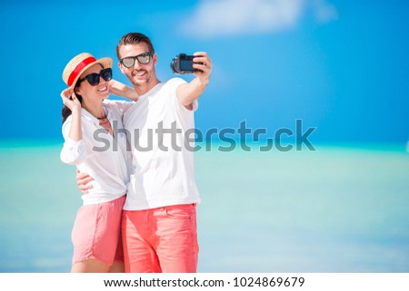 Selfie couple taking pictures on the beach. Tourists people taking travel photos on their holidays.