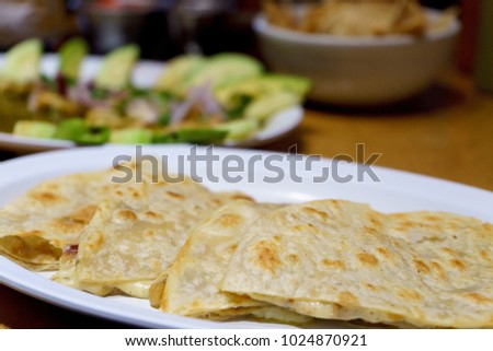 Mexican tacos of chicken with red and green chili in white sauce with avocado on a restaurant background.