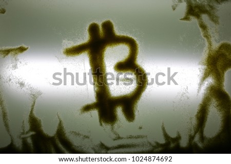 Bitcoin drawn with sand on the glass lighted surface. Financial growth cryptocurrency. Art and business. Original image of virtual cash sign.