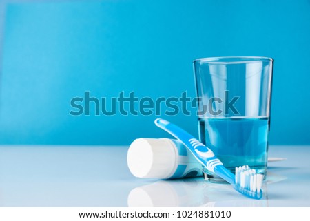 A blue toothbrush with toothpaste and glass of blue mouthwash on blue background with copy space, close-up. Dental oral hygiene concept Royalty-Free Stock Photo #1024881010