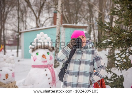 girl photographer in winter plays in the snow in the Park outdoors having fun outdoors