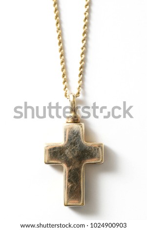 Gold cross necklace shot against a white background