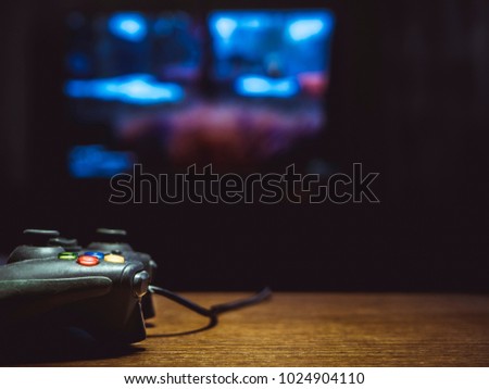 video game joystick gamepad on the table in front of tv Royalty-Free Stock Photo #1024904110