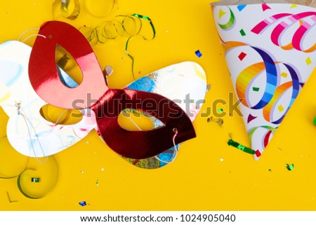 Bright colorful carnival or party scene of confetti and masks on yellow table. Flat lay, birthday or party scene.