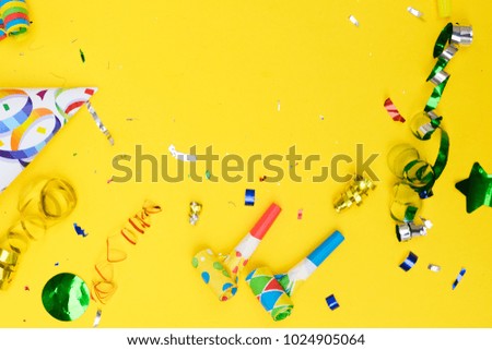 Bright colorful carnival or party scene border of metalic confetti on yellow table. Flat lay style, birthday or party greeting card with copy space.