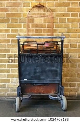 Close up of a trolley with an empty bird cage against a brick wall at Kings Cross Station. Royalty-Free Stock Photo #1024909198