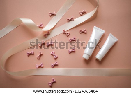 bows background on pink with cosmetic product packaging bottle. pastel ribbon and pretty girly. abstract wallpaper pattern.