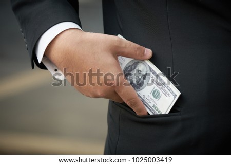Businessman wearing a black suit. Hold a dollar bill. Put in a pocket The bracelets of the business.using as background business concept with copy space for your text or design.