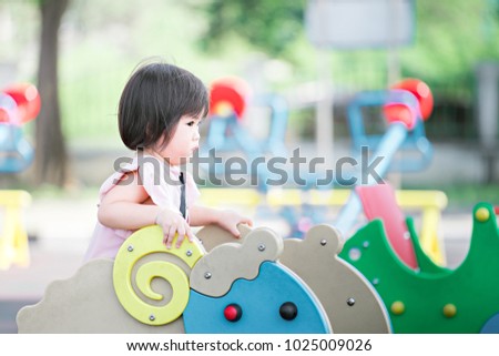 Asian baby girl in pink dress playing on the playground .She very enjoy to play.