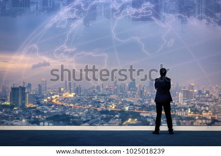 Vision concept. Successful businessman standing with hands crossed on chest, On top of building and looking through Cityscape Skyline Night Light. Royalty-Free Stock Photo #1025018239