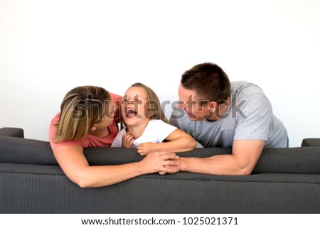 young beautiful and happy Caucasian couple with mother and father playing tickles on cheerful adorable 7 years old blond little girl in parents and daughter love and lifestyle concept