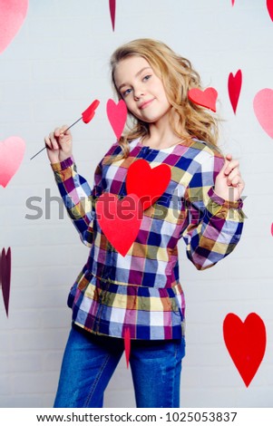 Valentine's Day concept. Happy pre-teen girl poses surrounded by little hearts. First love.