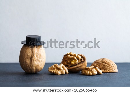 Senor walnuts black hats, half nutshell on stone and gray background. Creative food design poster. Macro view selective focus photo. Royalty-Free Stock Photo #1025065465