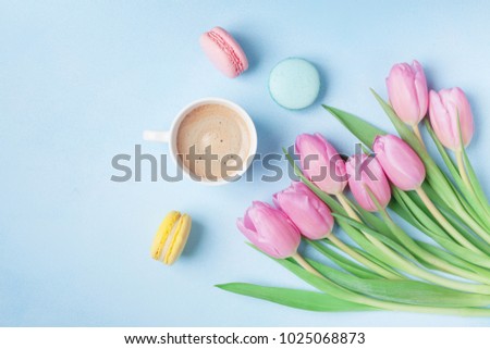 Spring tulip flowers, colorful macaroons and coffee on blue pastel table top view. Beautiful breakfast on Mothers or Womans day. Flat lay.