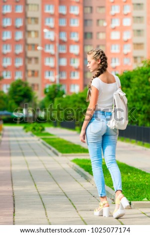 a young girl is walking around the city with a backpack, a back view