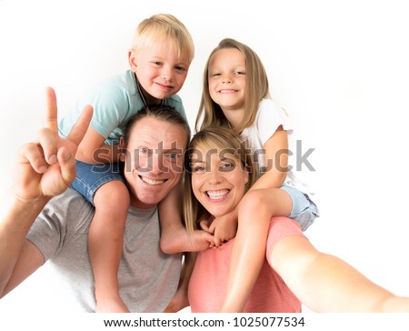 lovely young couple taking selfie photo self portrait with mobile phone carrying son and daughter on shoulders posing happy smiling isolated on white in family lifestyle concept 