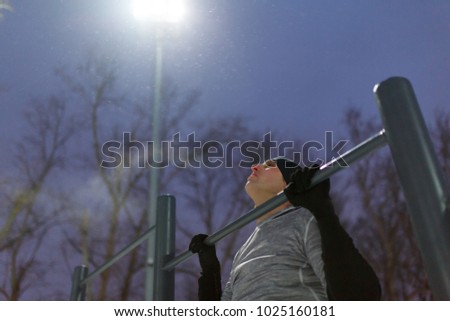 Picture of sports man pulling up on bar in evening at moon