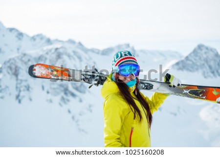 Photo of athlete woman with skis on her shoulder against background of snowy hill