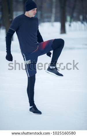 Photo of sportive man doing stretching in winter