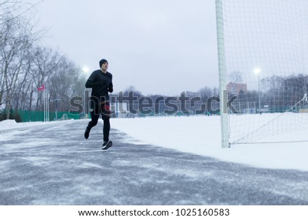 Image of sporty man running at stadium in winter