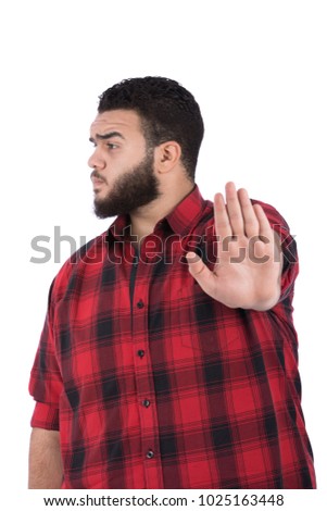 A young fat man raising his palm on the front of the camera doing the stop sign, in a side shot of a serious face, isolated on a white background.