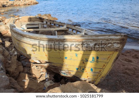 Abandoned wooden fishing boat on the beach next to the sea shore
