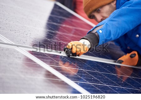 Selective focus on the hands of a professional male electrician installing solar panels working on alternative energy sources farm clean green environment friendly energy modern technology. Royalty-Free Stock Photo #1025196820