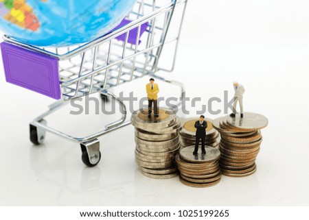 Miniature people: Businessman standing on stack of coins, shopping cart with world map for retail business. Image use for online and offline shopping, marketing place world wide, business concept.