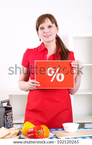 Young woman cooking fresh meal at home and holding percent sign