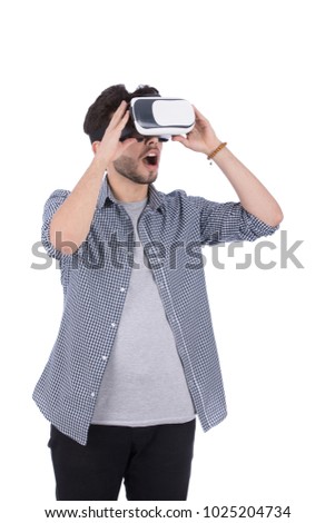 A young man standing and wearing the VR glasses, opened his mouth looking surprised, isolated on a white background.