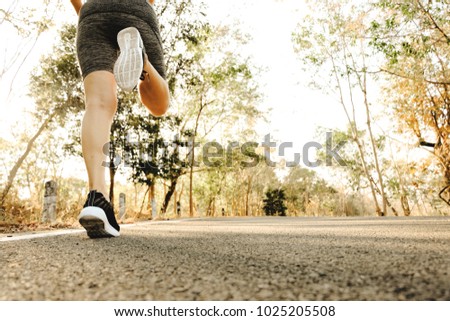 Sports woman legs in running movement, Close up picture of feet of young woman relax walking in the park on the great holiday, Healthy lifestyle concept.