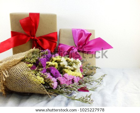 craft paper gift box with ribbon bow and flower bouquet with fabric texture