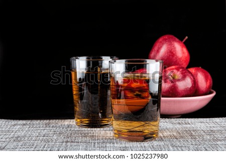 Two glasses of apple juice on a black background
