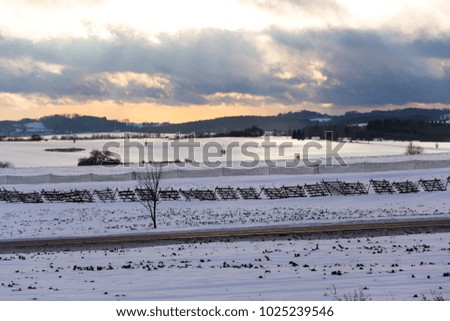 Wooden and plastic snow barriers close to road in snowy landscape during sunset, commuter traffic weather forecast news conceptt