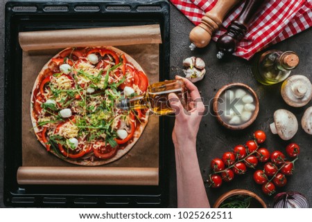 cropped shot of woman pouring oil onto delicious pizza on concrete table