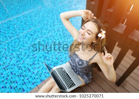 pretty woman resting and stretching hands after hard working on laptop online. Sunny picture on background of swimming pool. Concept of working remotely