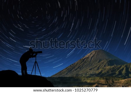 silhouette of a photographer who shoots star trail on background.