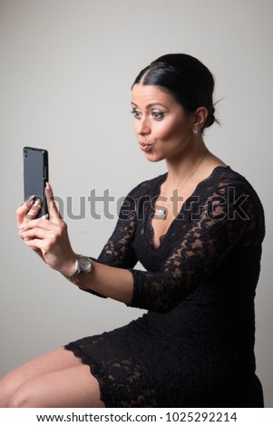 Young woman taking a selfie, making a duck face, posting online to social media