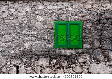 stony house wall with green window
