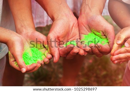 Holi festival. Woman and children are holding green powder in their hands. Lime green colors. Close-up photo. Colorful life. Happy family. 