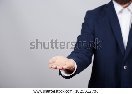 Man's hand wearing suit showing a sign at studio background, close up, business concept, gestures, holding product, copy space.