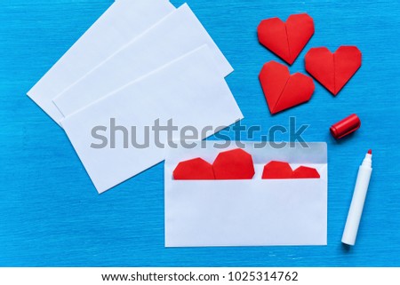 Hearts are in white envelopes on a turquoise table. Hearts in an envelope..