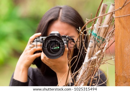 Young woman stalking and taking pictures with her camera, at outside