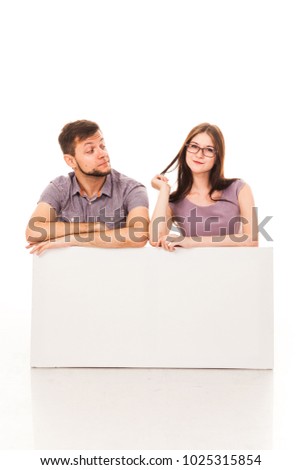 A guy and a girl are posing with a white sign in their hands. Isolated image. For advertising, logo, text. Emotional photo. Actor play.