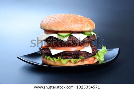 Burger with cutlet, salad, tomatoes and cheese on dark background
